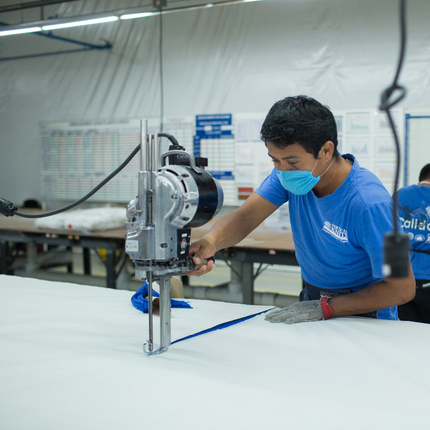 Trabajador de fábrica cortando tela