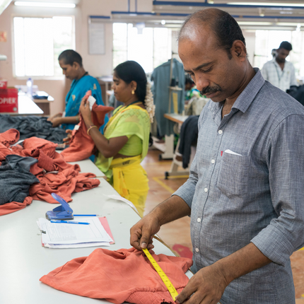 Un hombre midiendo tela en una fábrica Fair Trade Certified