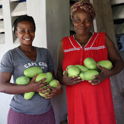 Dos mujeres con mangos de una granja de mangos de comercio justo en Haití