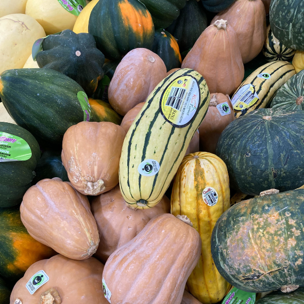 A bag of red, green, and yellow organic peppers from Whole Foods featuring the Fair Trade Certified label.