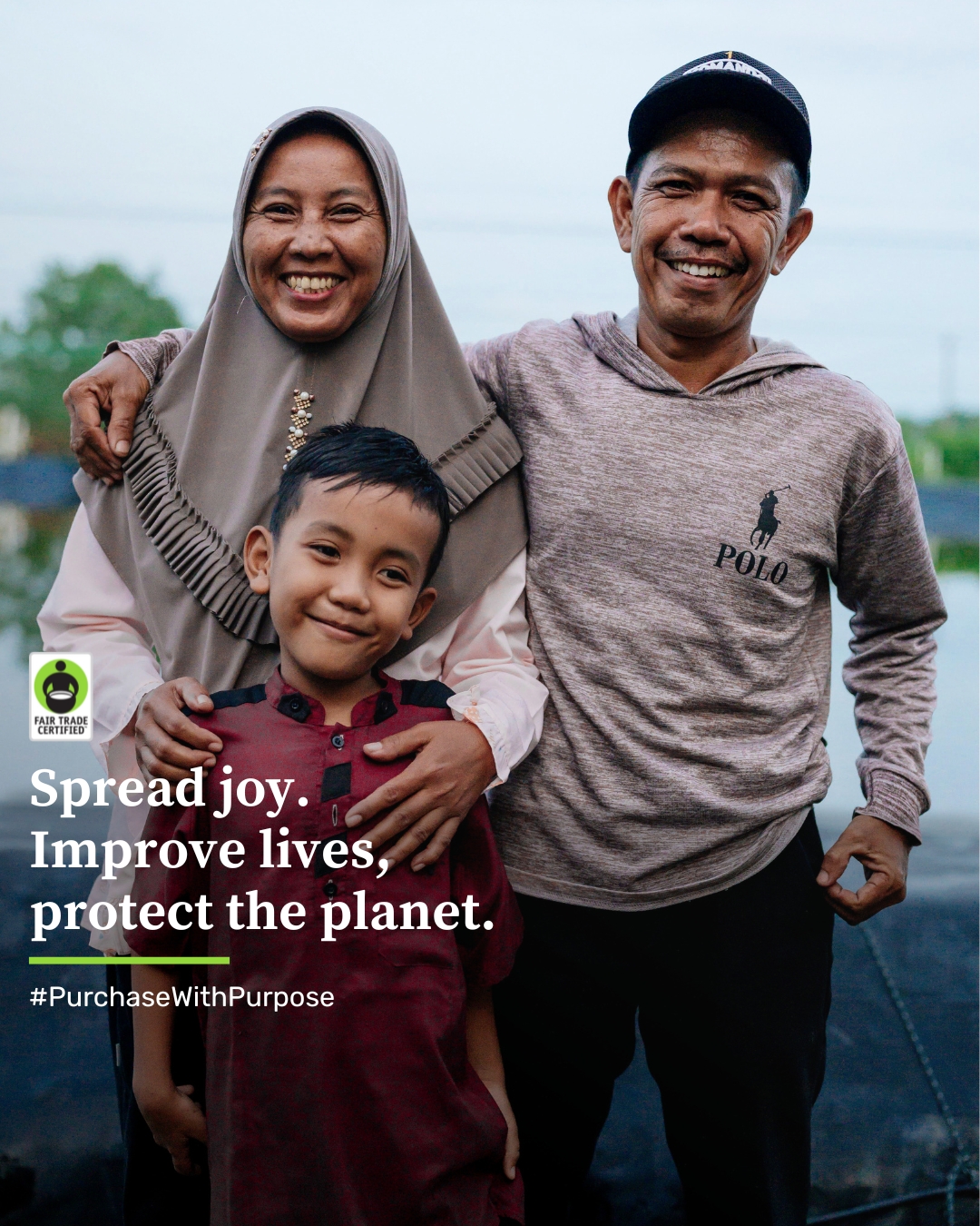 Una pareja de Indonesia de pie con su hijo sonriendo. Texto adjunto: Esparcir alegría. Mejorar vidas, proteger el planeta. #CompreConPropósito, creado por Fair Trade USA