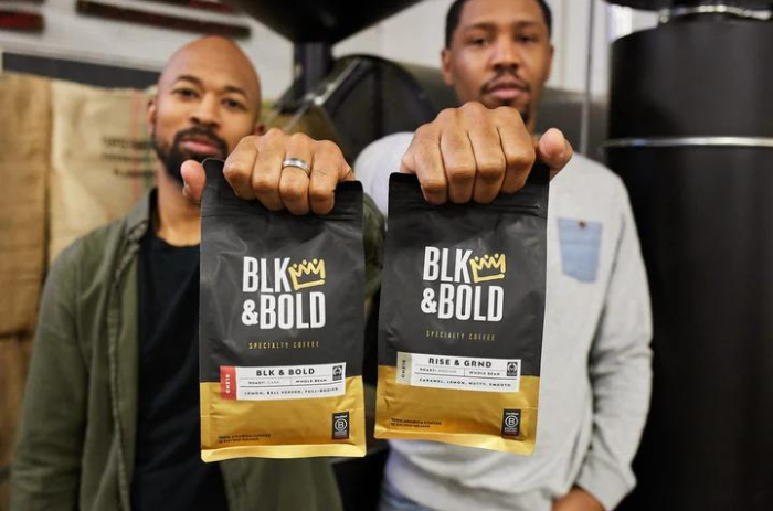 Los cofundadores de BLK & Bold Specialty Beverages, Pernell y Rod, sosteniendo bolsas de café.