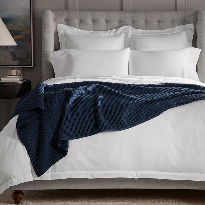 A blue Boll & Branch Waffle Bed Blanket laying across a bed.