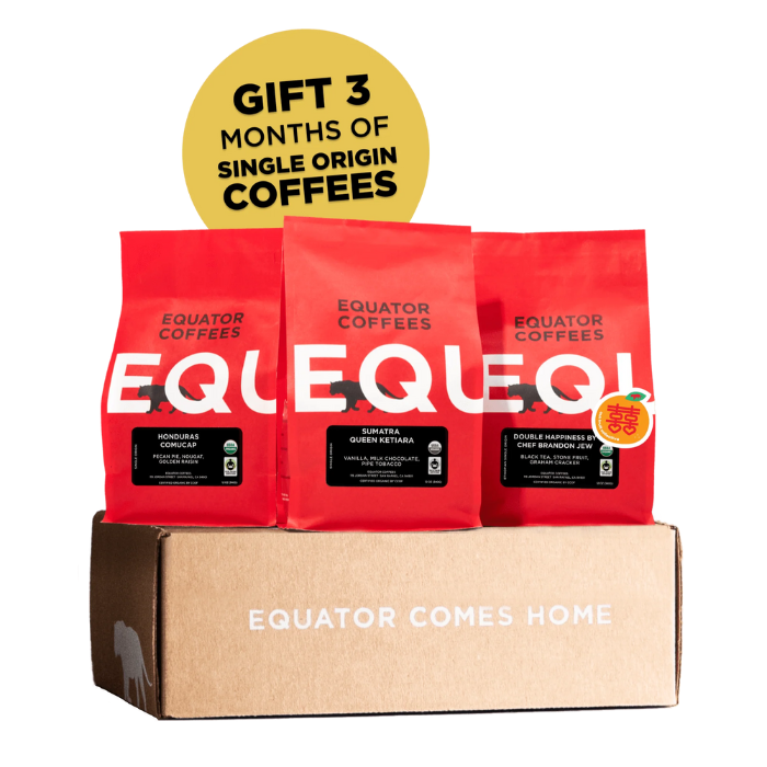 Tres bolsas de Equator Coffee sobre una caja de reparto.