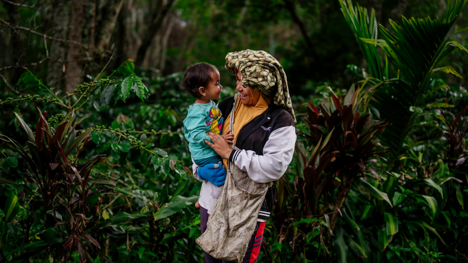 Mother holding her child outside on a coffee farm in Indonesia.