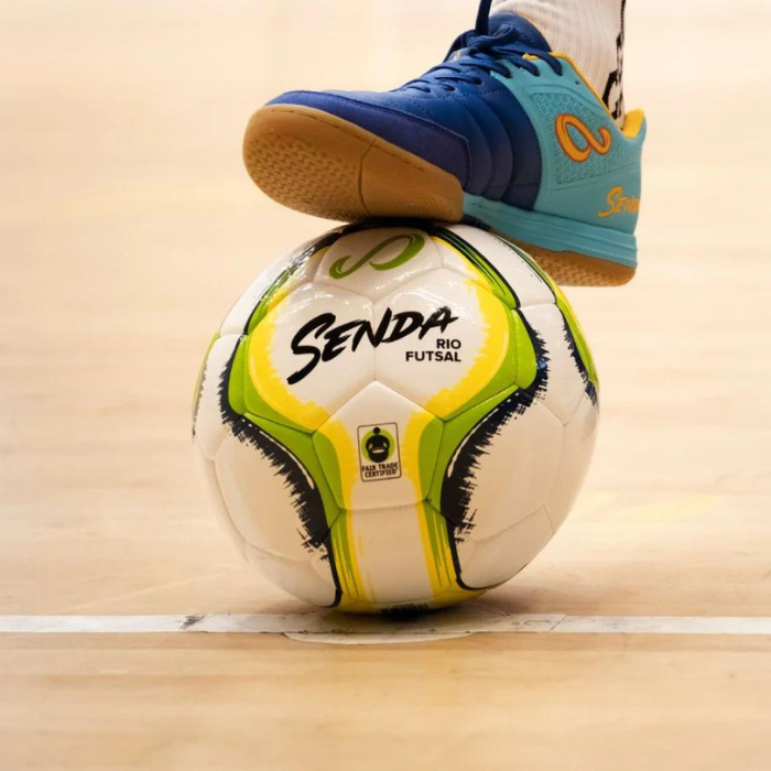 A foot resting on top of a Senda futsal match ball.
