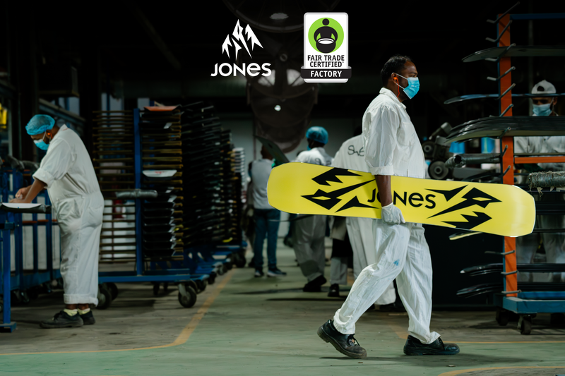 Un trabajador de una fábrica que lleva una tabla de snowboard Jones en una fábrica certificada de Comercio Justo